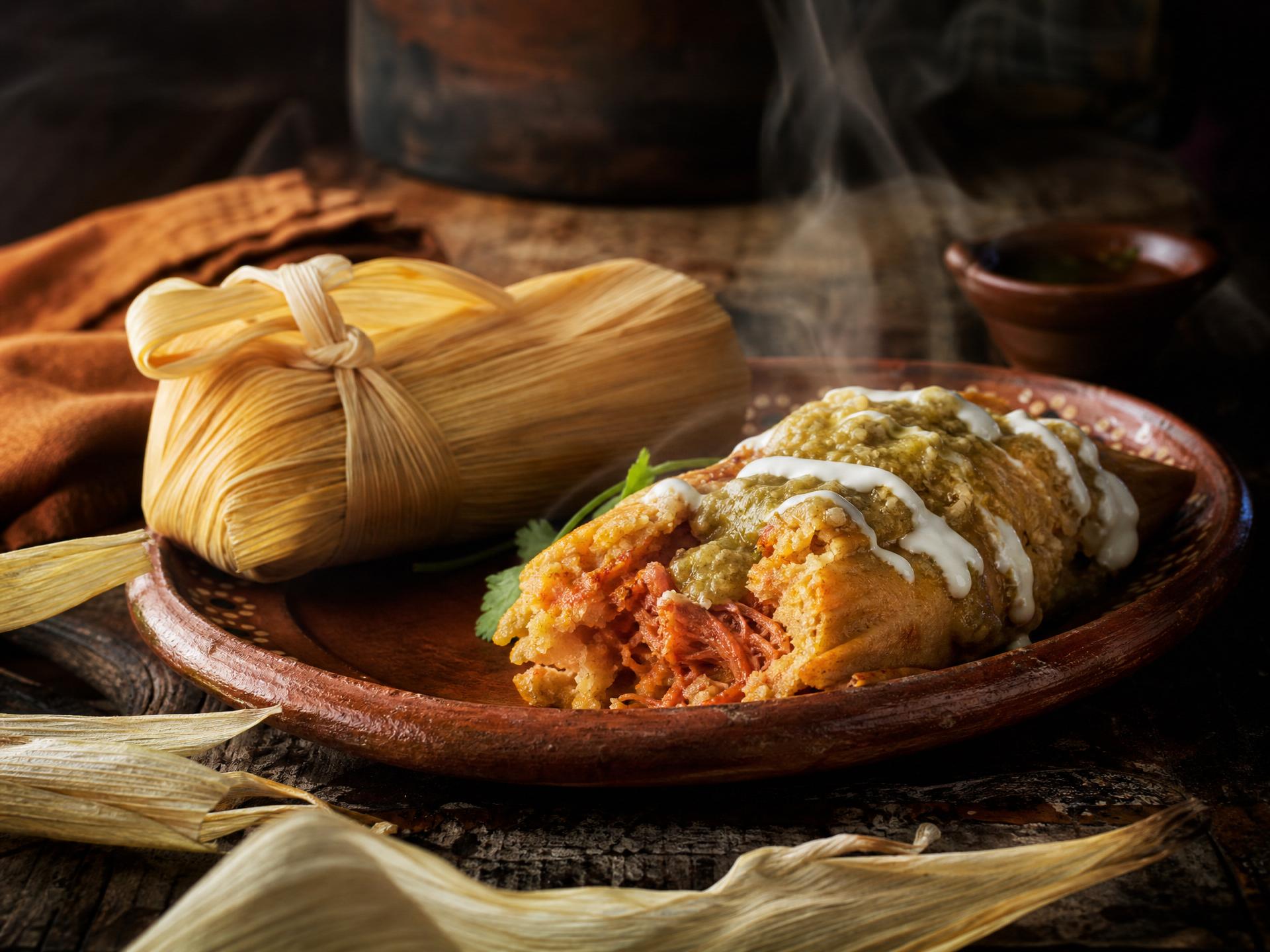 Red beef tamales unwrapped on corn husks