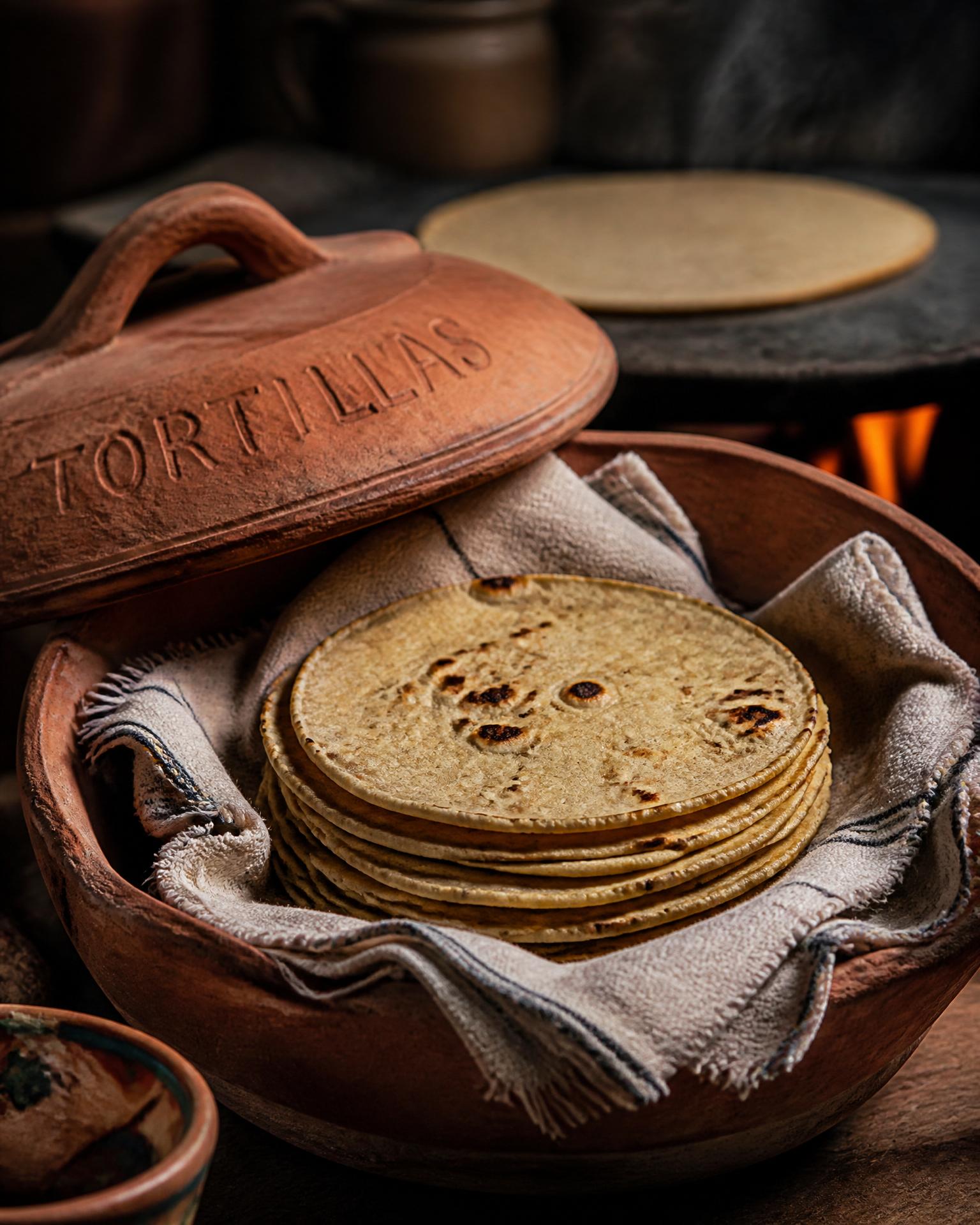 Fresh corn tortillas stacked in a clay tortillero